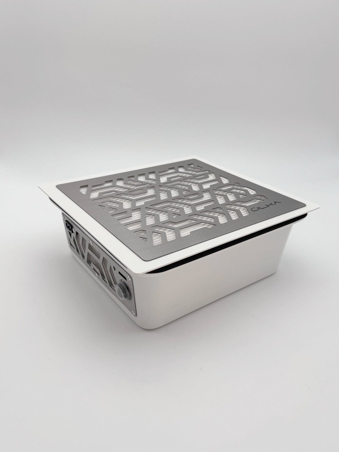 Pochłaniacz pyłu ÜLKA Premium do zabudowy w kolorze białym z metalową kratką o geometrycznym wzorze.