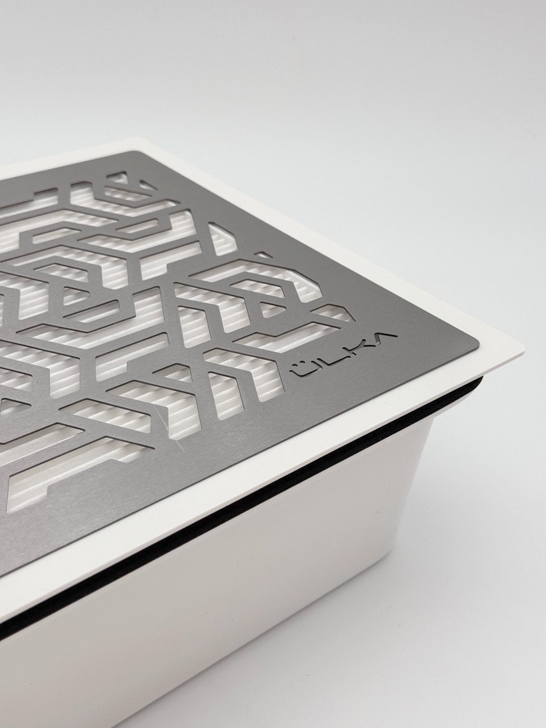 Zbliżenie kratki pochłaniacza pyłu ÜLKA Premium z logo i filtrem HEPA widocznym pod spodem.